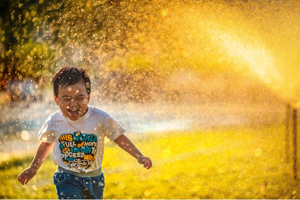 child laughing and running through water, face looking at the camera