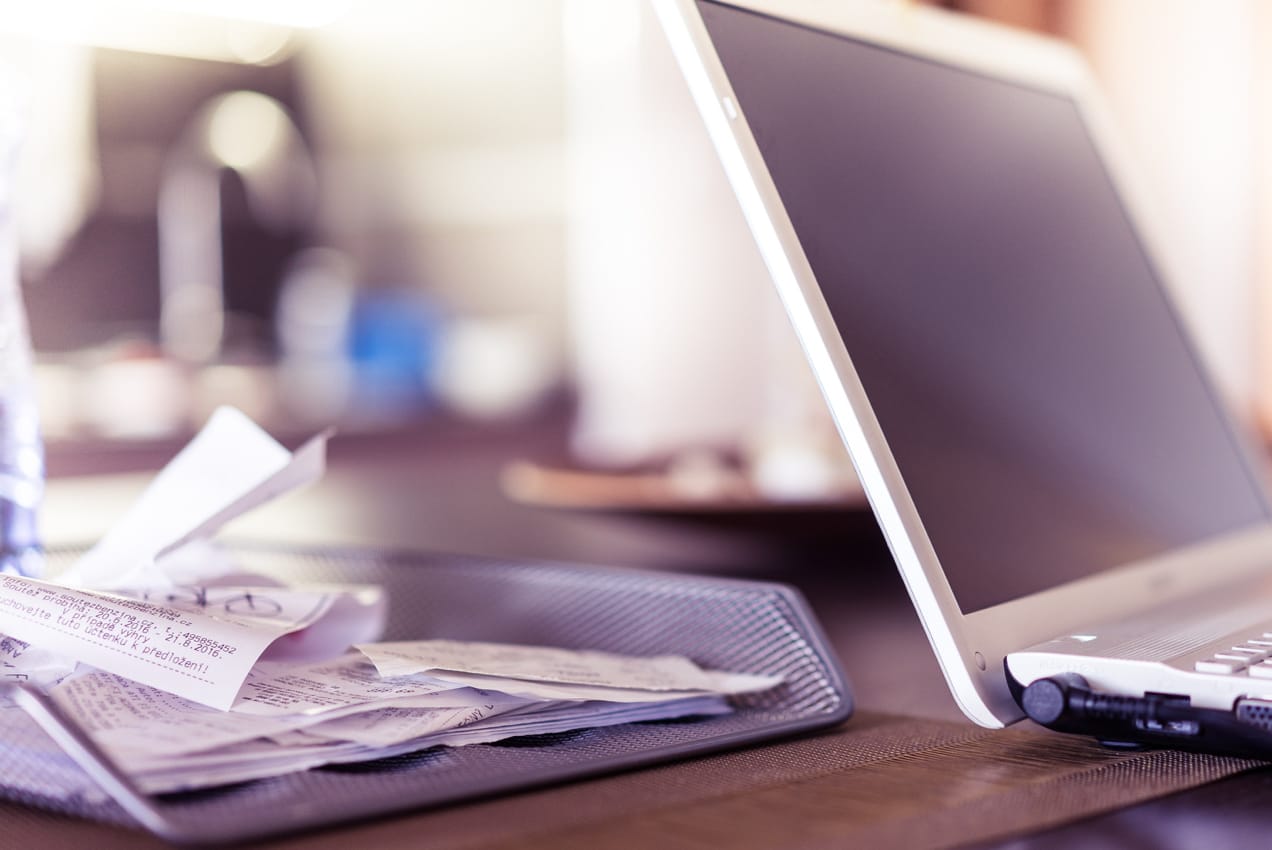 stack of receipts next to a laptop