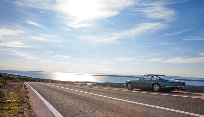 A car parked on the side of the highway next to a body of water.